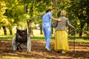 Older adults join a gentle chair exercise class in a bright assisted living common room.